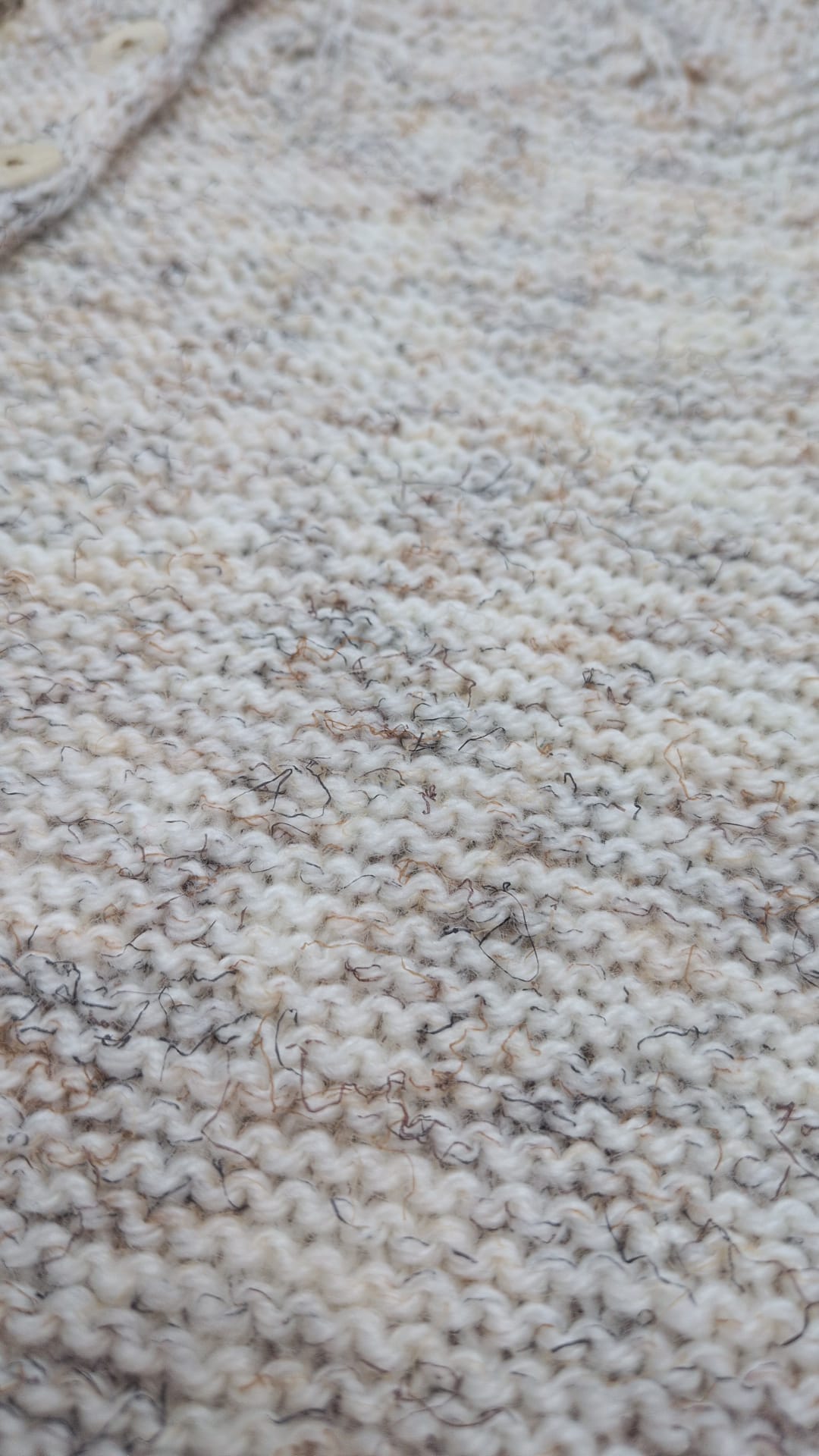 Close-up of a chunky knit fabric in a heathered cream, beige, and light brown colorway, showing the detailed knit texture.